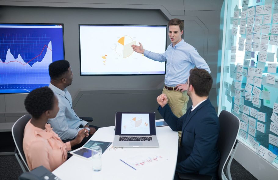 formation Homme présentant des données à un groupe dans une salle de réunion moderne.